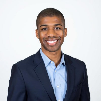 Man wearing a dark suit and light blue shirt against a white background